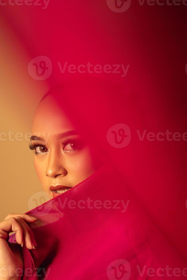 en skön balinesisk kvinna täckt henne smink ansikte med röd tyg från de klänning foto