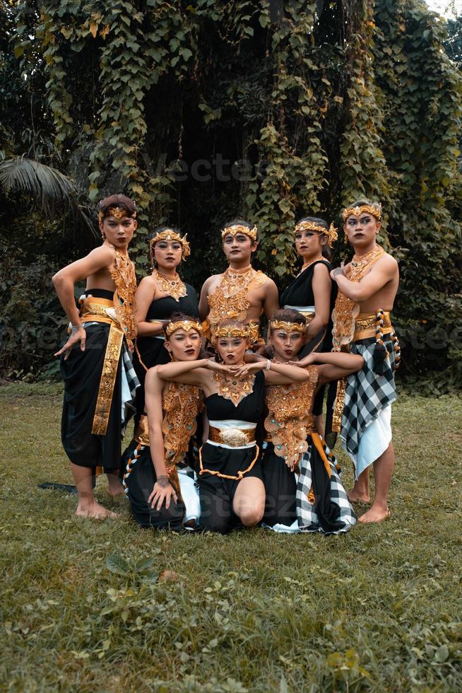 en grupp av balinesisk människor poser tillsammans med en Lycklig ansikte medan bär gyllene kostymer efter de prestanda foto