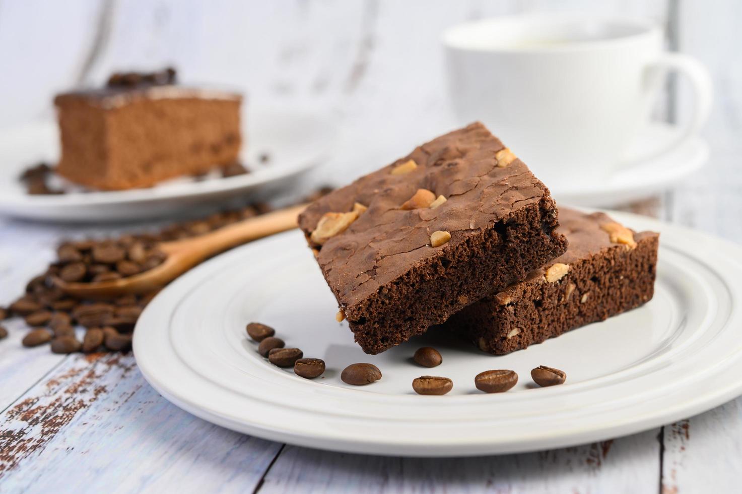 choklad brownies på en vit platta och kaffebönor på en träsked foto