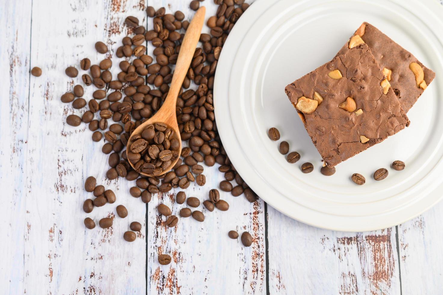 choklad brownies på en vit platta och kaffebönor på en träsked foto