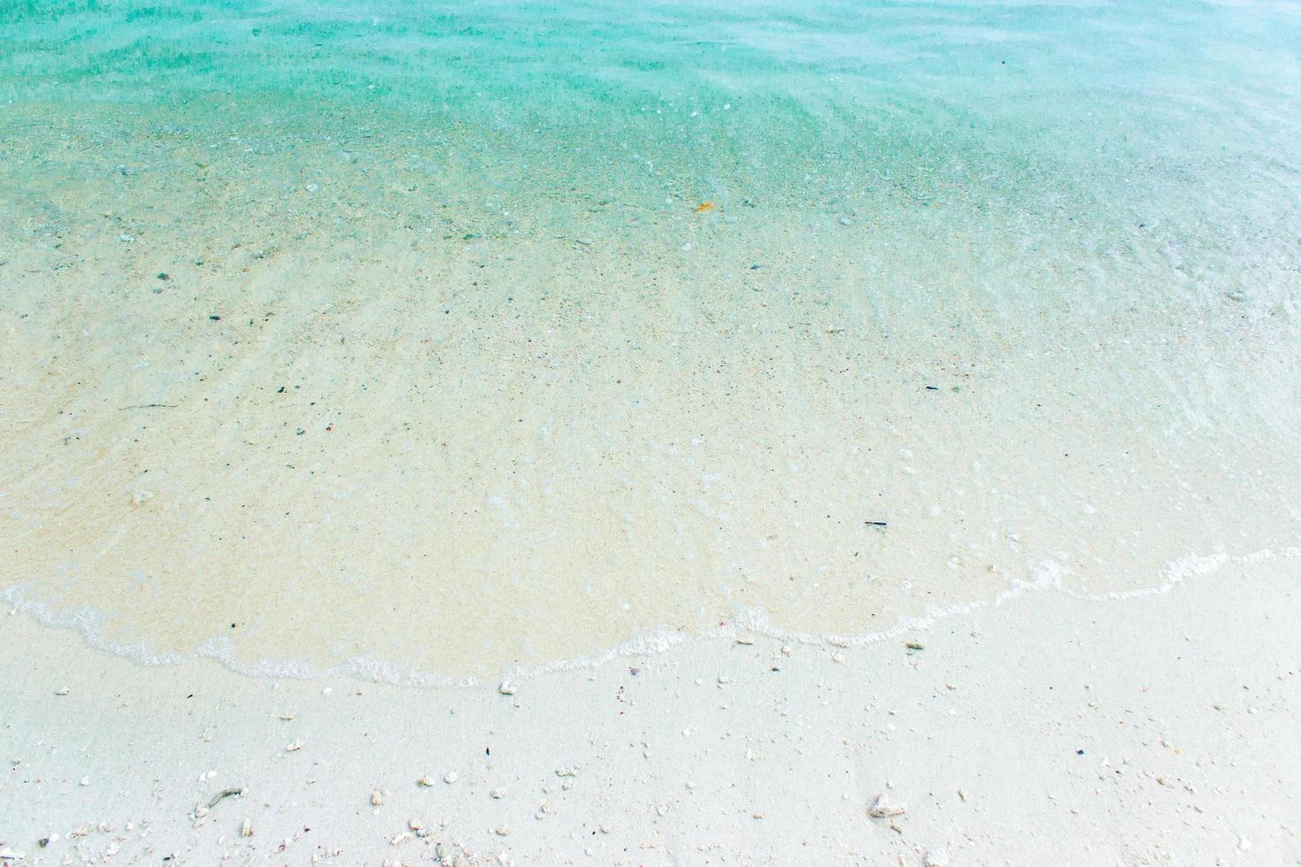 vit sand med blått vatten foto