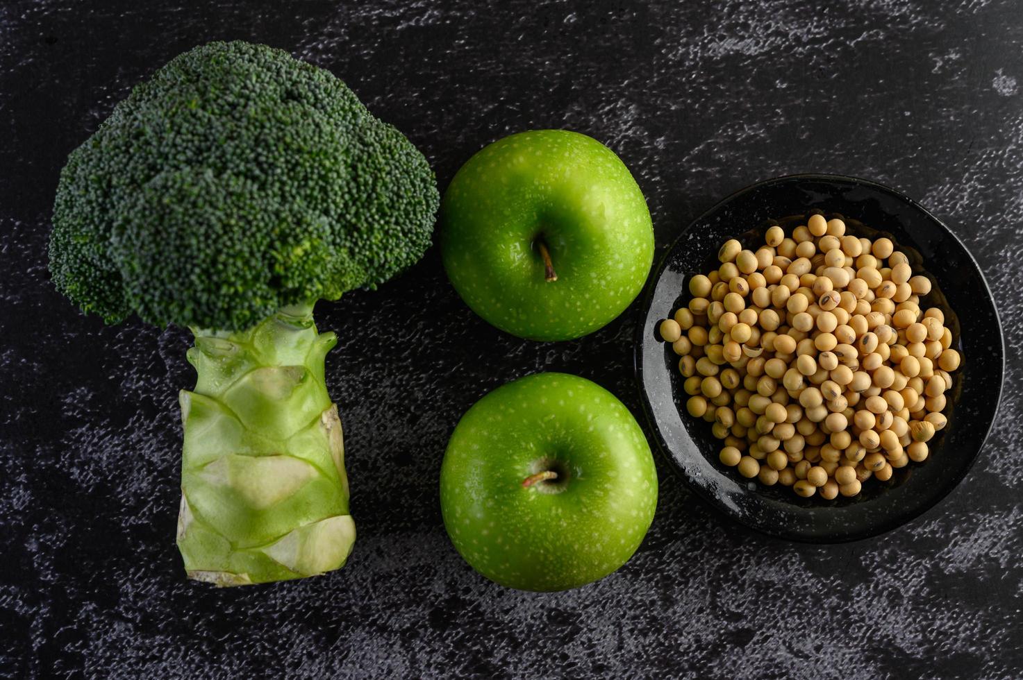 broccoli, äpple och bönor på en svart cementgolvbakgrund foto