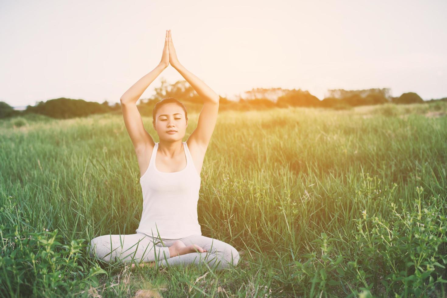 ung kvinna i yoga poserar öva meditation i ängarna foto