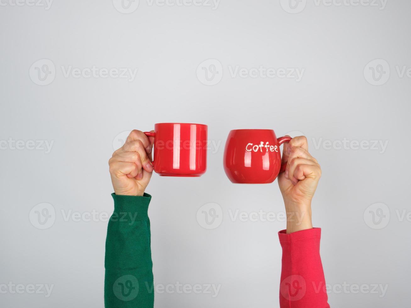 två händer i en Tröja innehav röd keramisk muggar foto