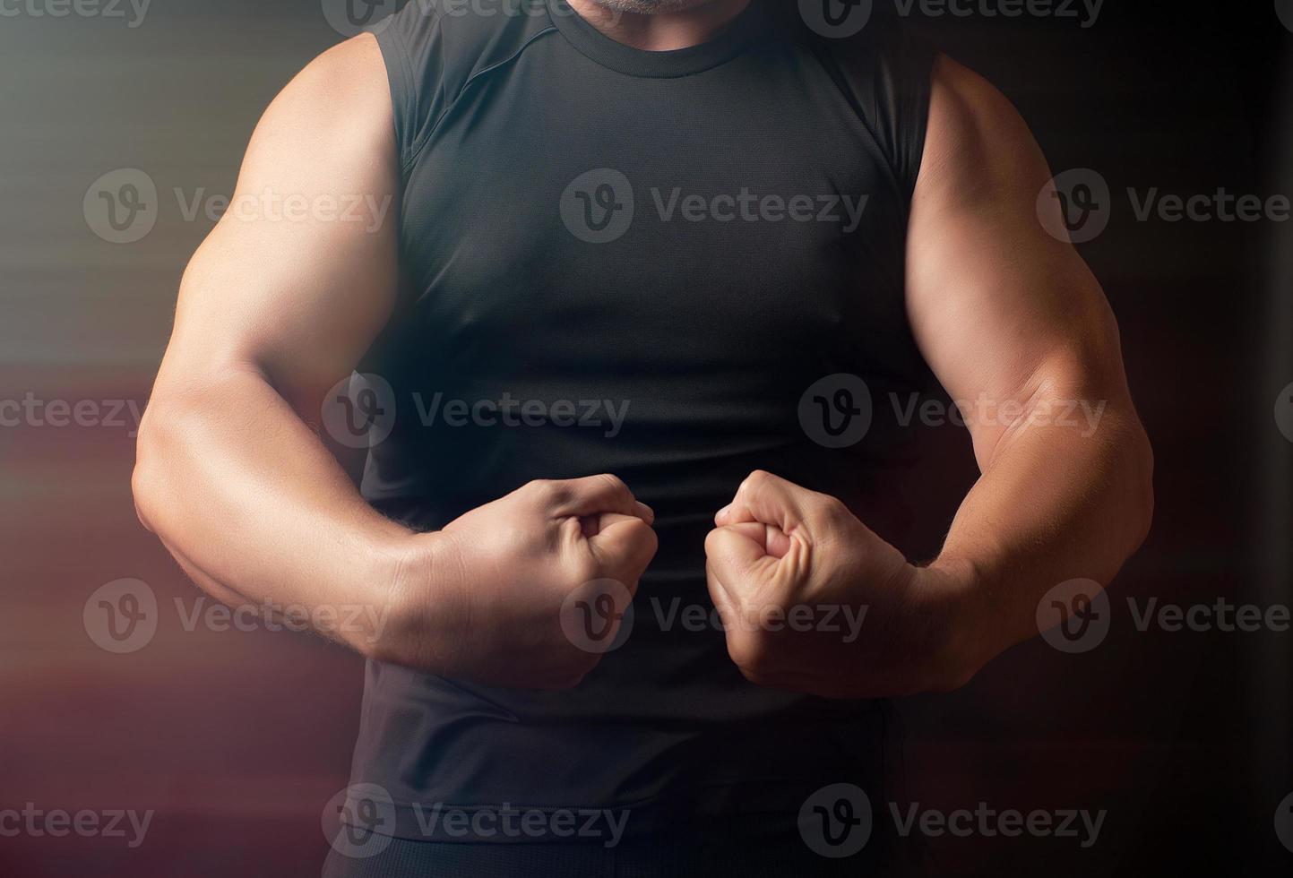 vuxen man med en sporter figur i svart kläder spänd hans muskler i hans vapen foto
