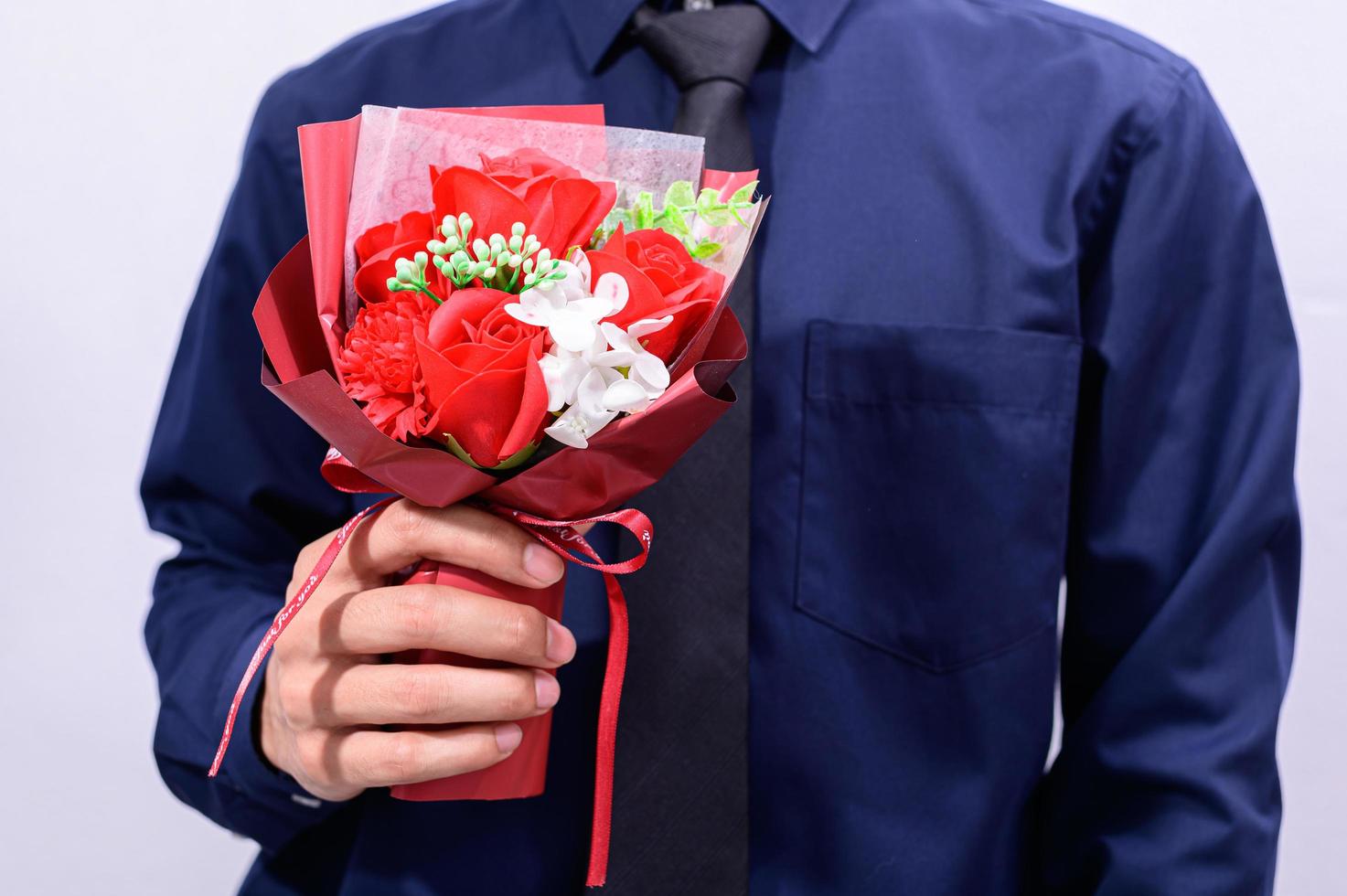 man som bär en kostym som håller blommor foto