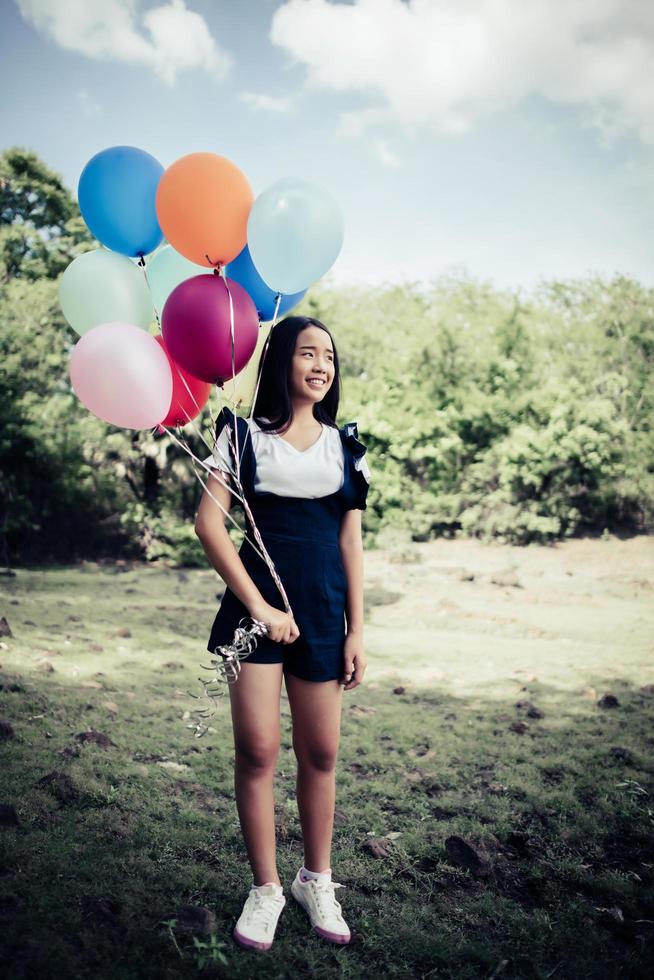 ung flicka som håller färgglada ballonger i naturen foto