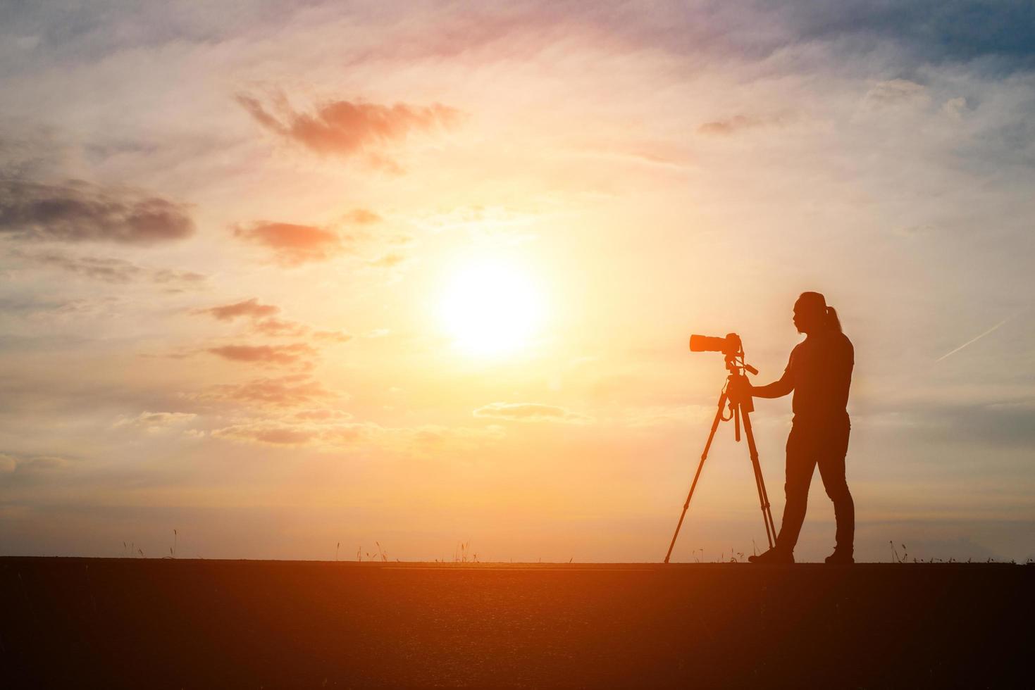 silhuett av en fotograf som skjuter vid solnedgången foto