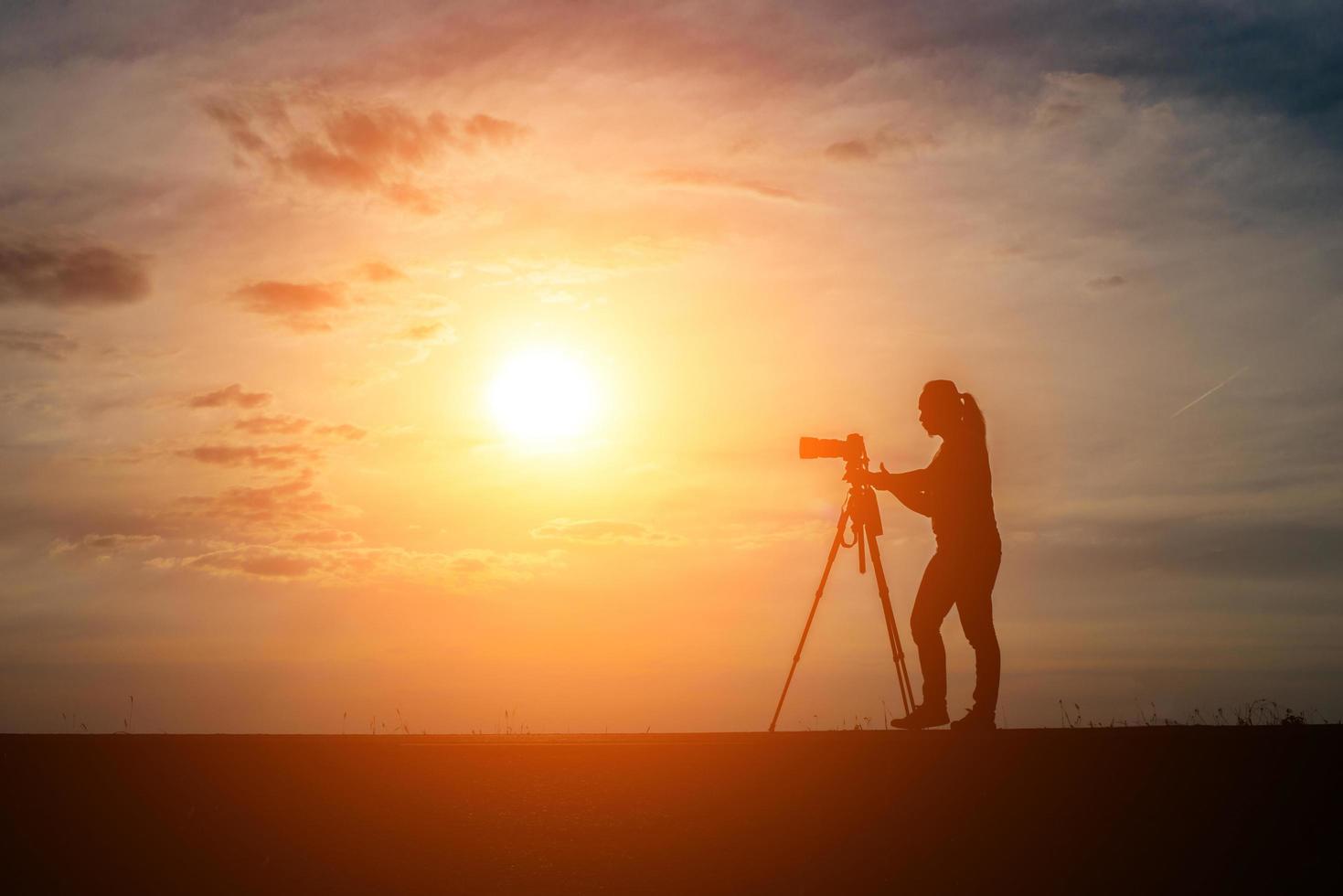 silhuett av en fotograf som skjuter vid solnedgången foto