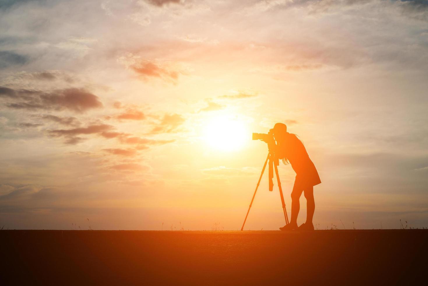 silhuett av en fotograf som skjuter vid solnedgången foto