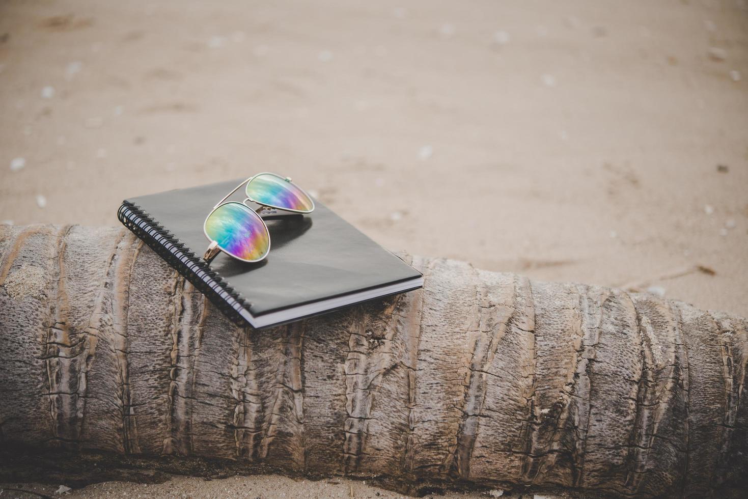 en anteckningsbok och glasögon på stranden foto