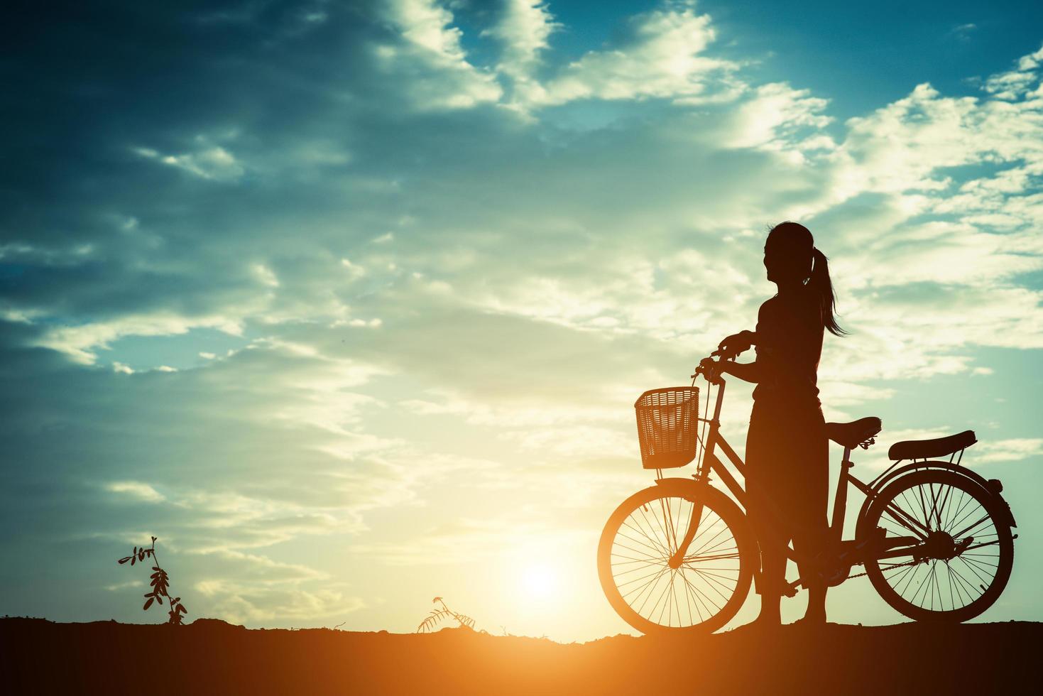 silhuett av en kvinna med en cykel och vacker himmel foto