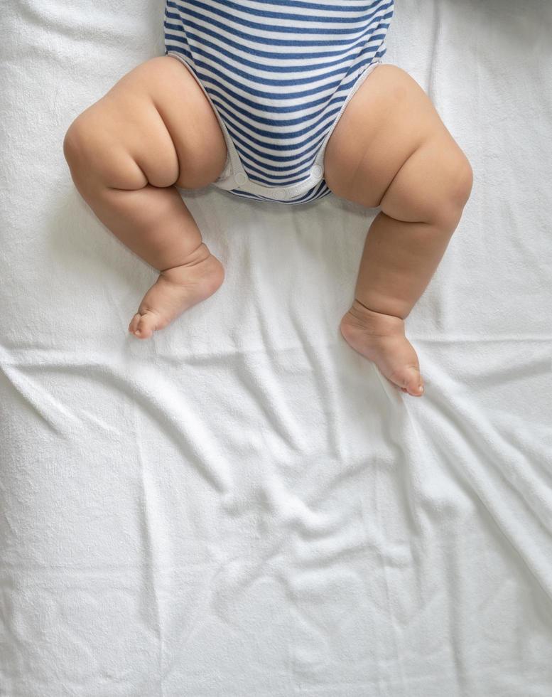 barnets fötter i en vit säng foto