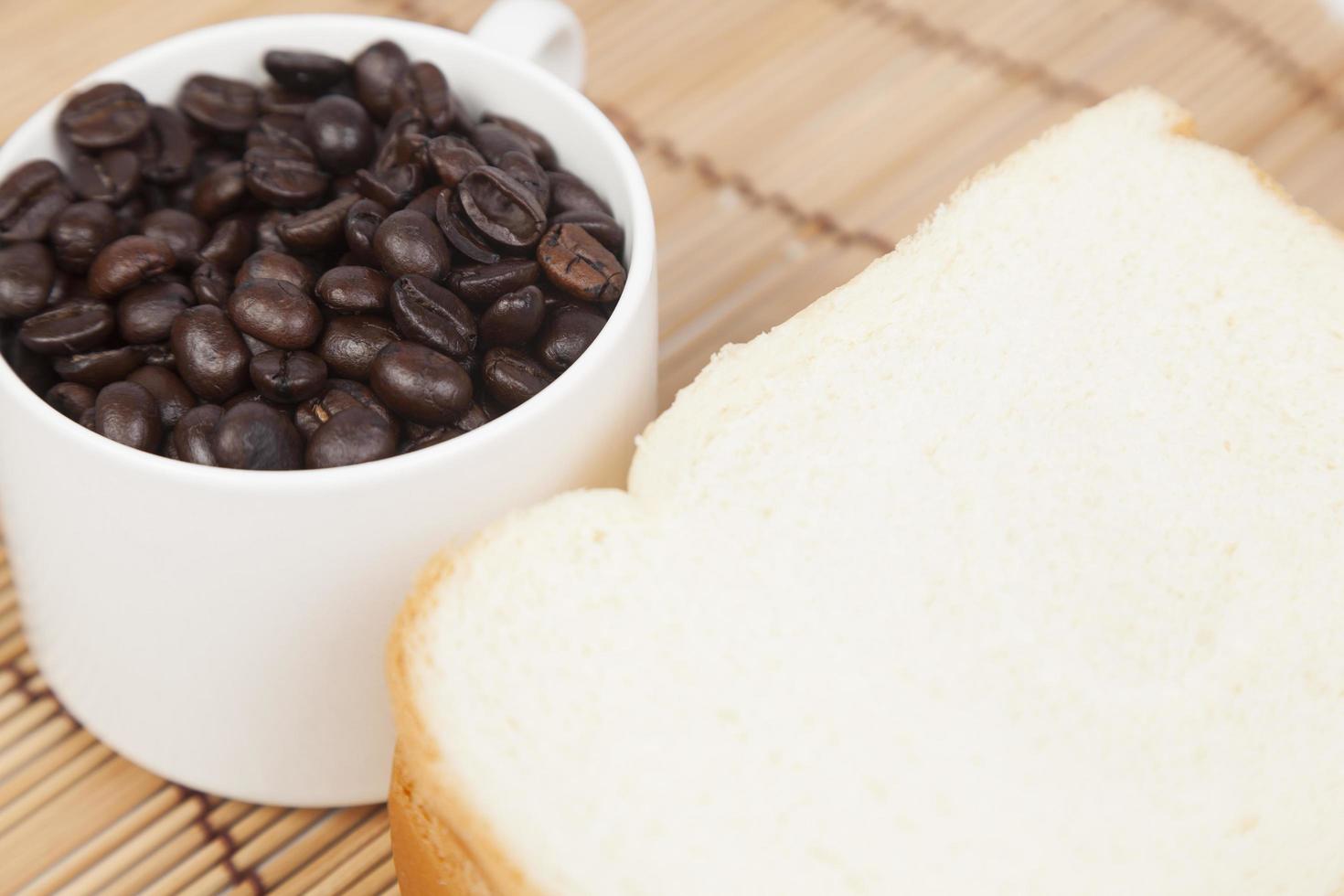 bröd och kopp med kaffebönor foto