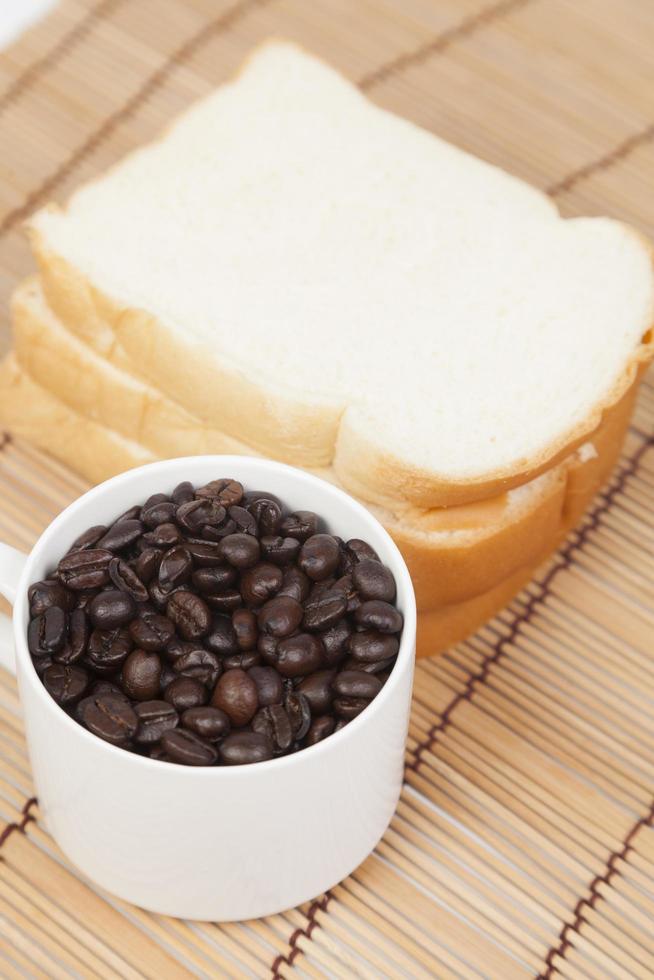 bröd och kopp med kaffebönor foto