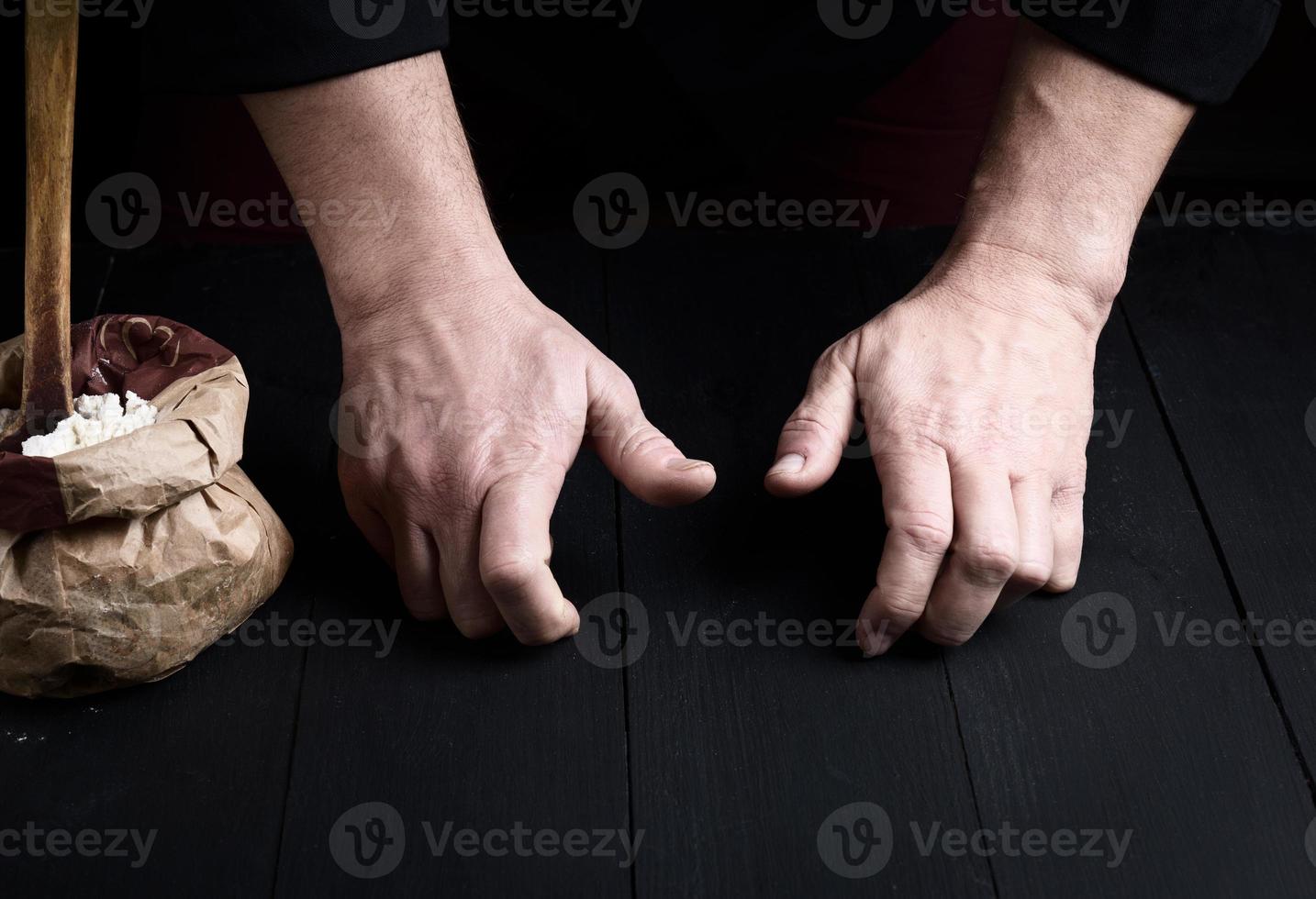 två manlig händer över en svart trä- tabell foto