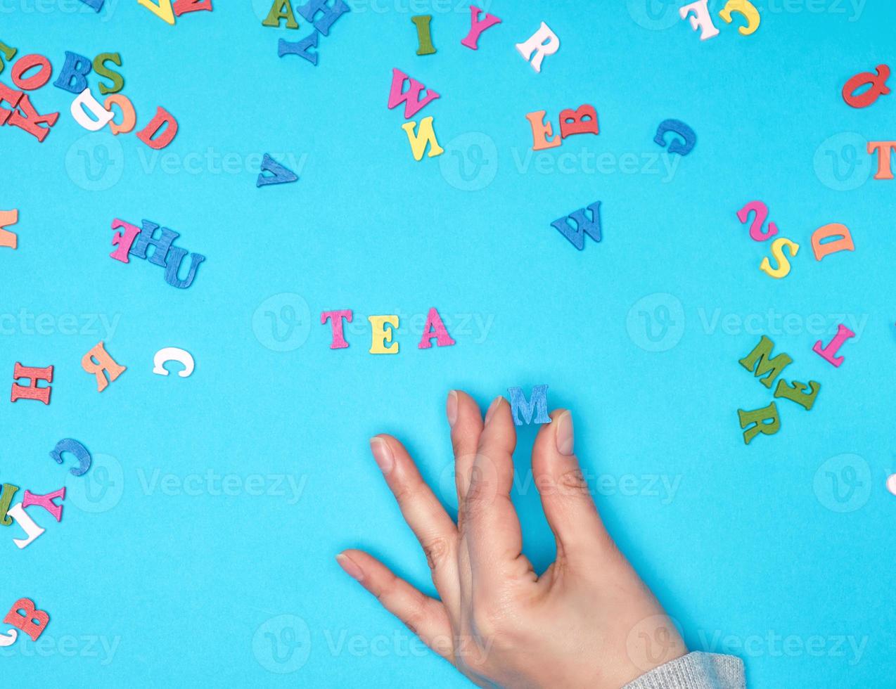 kvinna hand och flerfärgad trä- brev av de engelsk alfabet foto