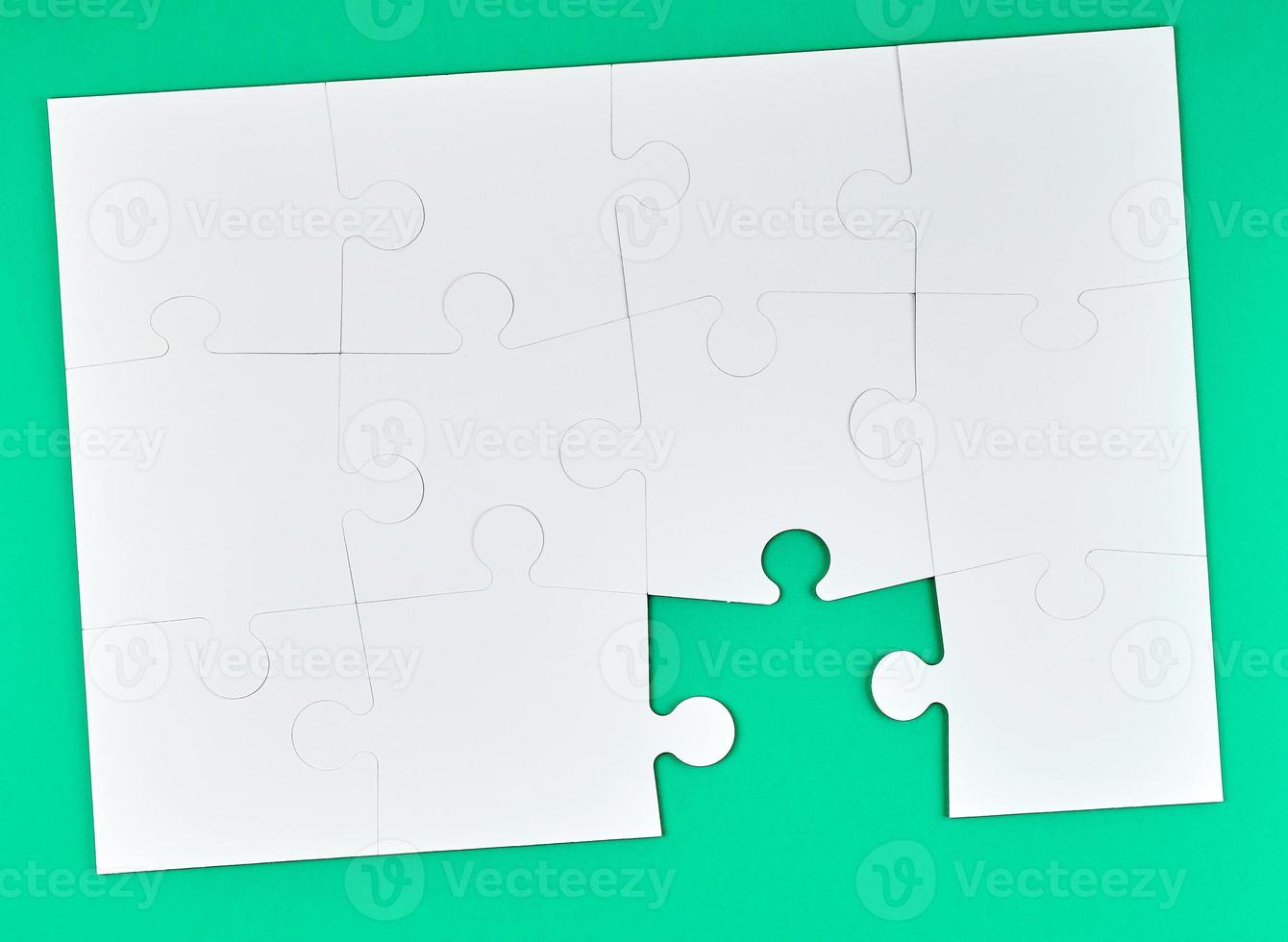 spel av pussel tillverkad av vit papper bitar sammankopplade på en grön bakgrund foto