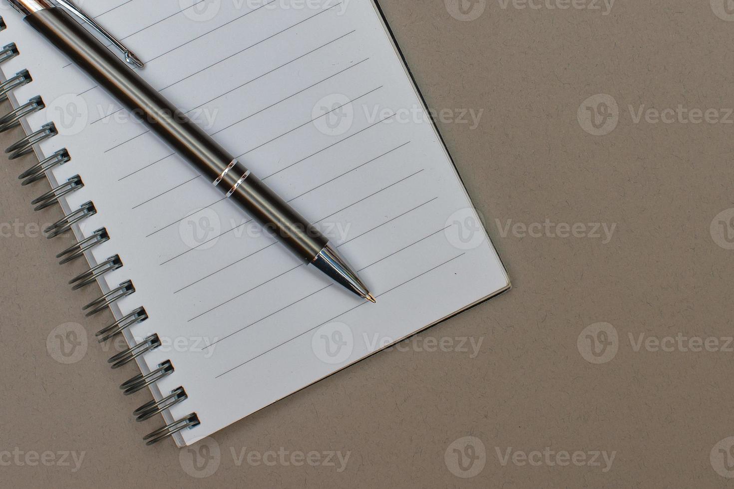 en anteckningsbok med en tom sida och en penna vilar på den foto