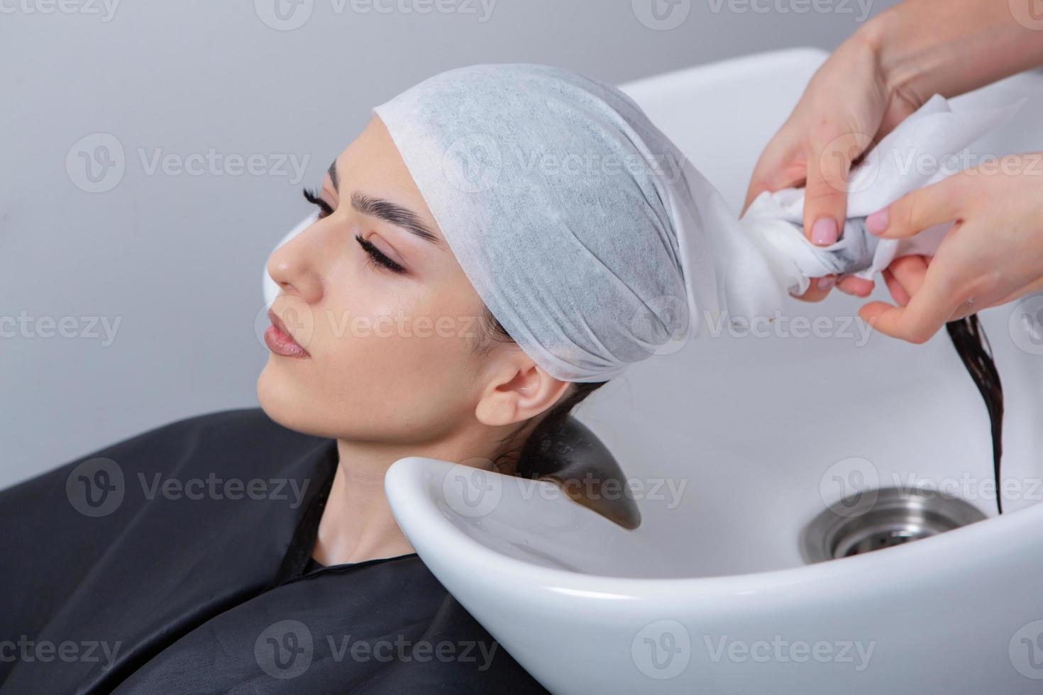 professionell frisör tvättning hår av ung kvinna i skönhet salong. stänga upp av kvinnas hår i skönhet salong, frisyr begrepp foto