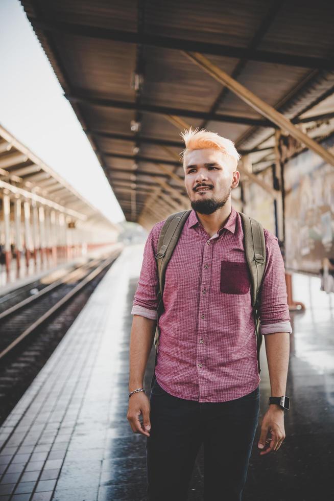 ung hipster man går genom tågstationen foto