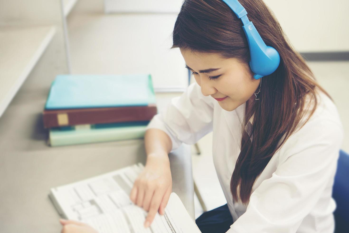 ung asiatisk student läser i biblioteket foto