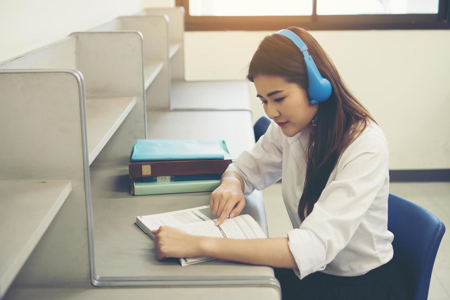 ung asiatisk student läser i biblioteket foto