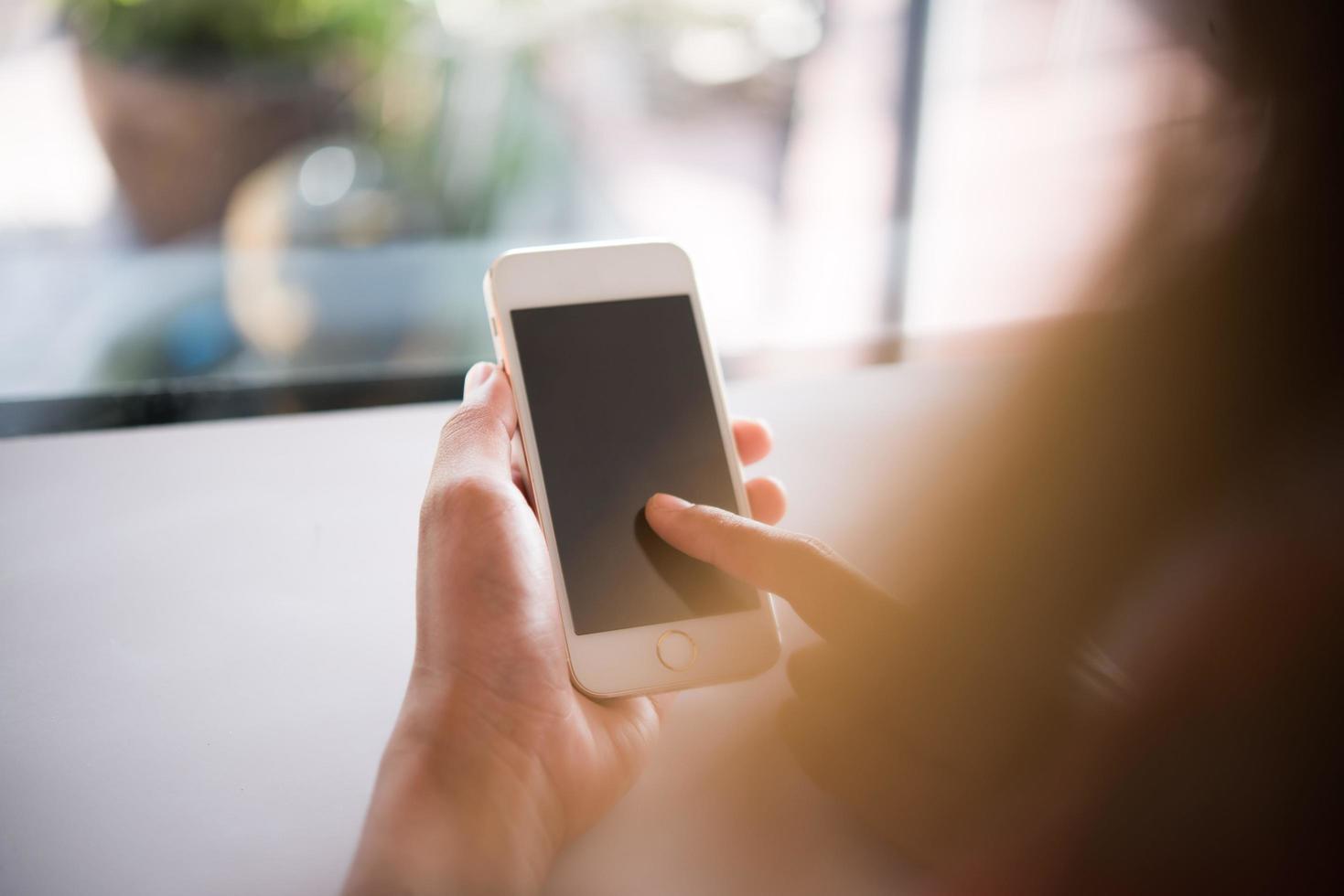 närbild av kvinnans händer som håller mobiltelefonen med blank skärm för kopieringsutrymme foto