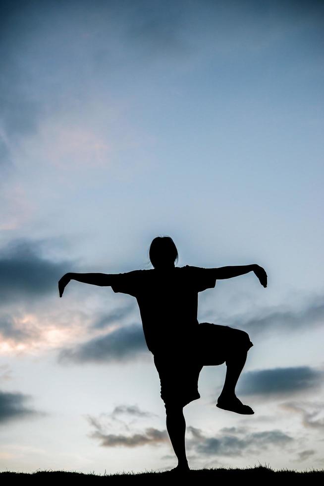 silhuett av ung man gör yoga vid solnedgången foto