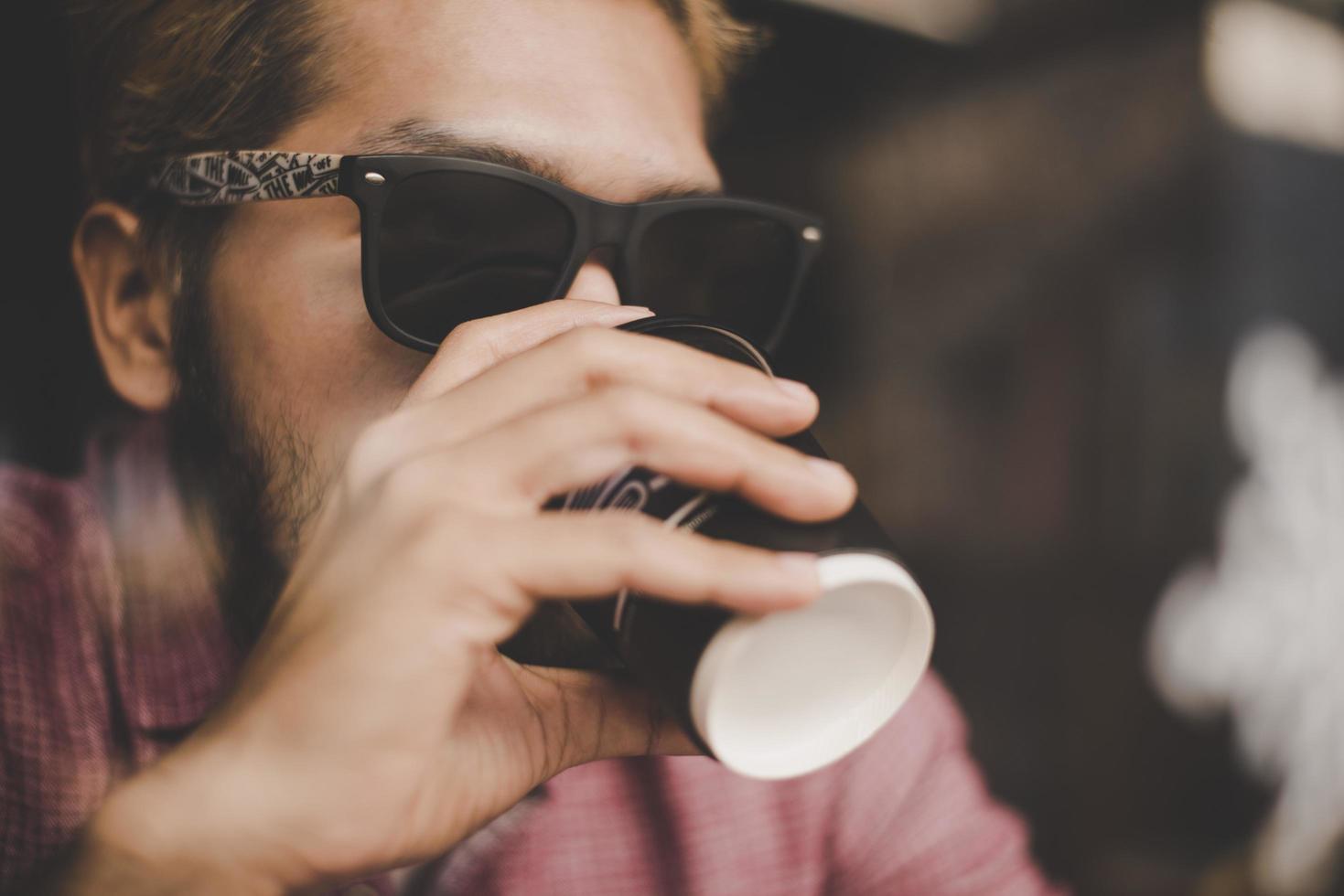 ung man sitter på ett kafé och dricker en kaffe foto