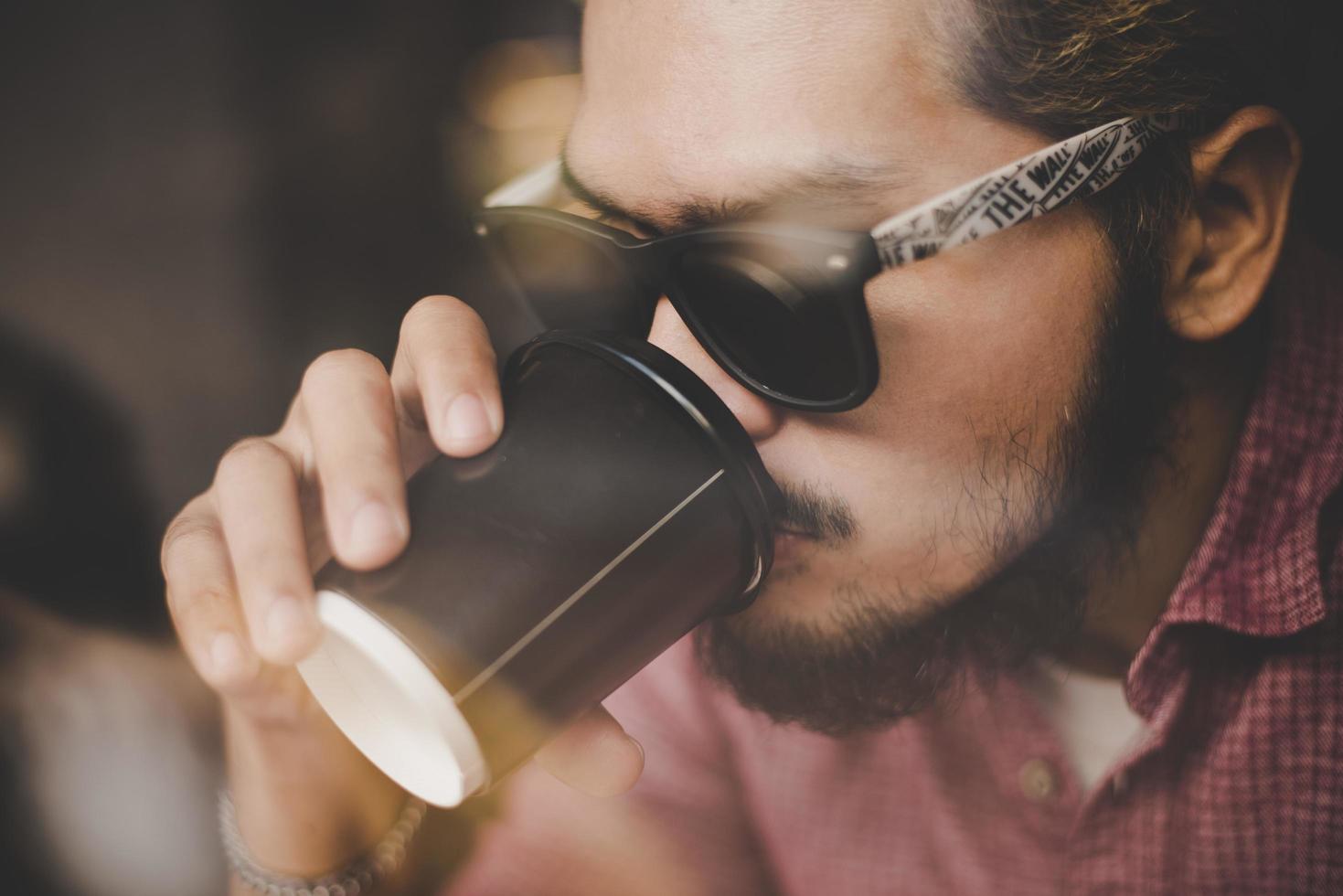 ung man sitter på ett kafé och dricker en kaffe foto