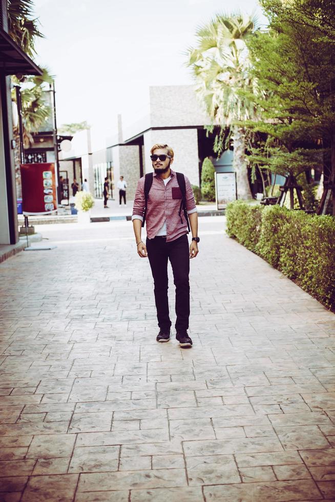 porträtt av en stilig hipster man i jeans och solglasögon promenader foto