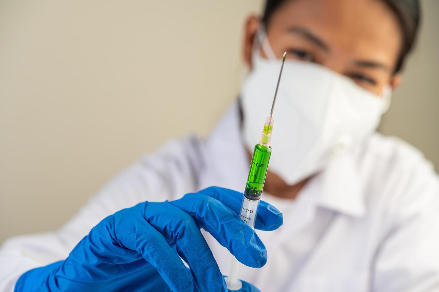 forskare som bär skyddsmasker och handskar som håller en spruta med ett vaccin för att förhindra covid-19 foto