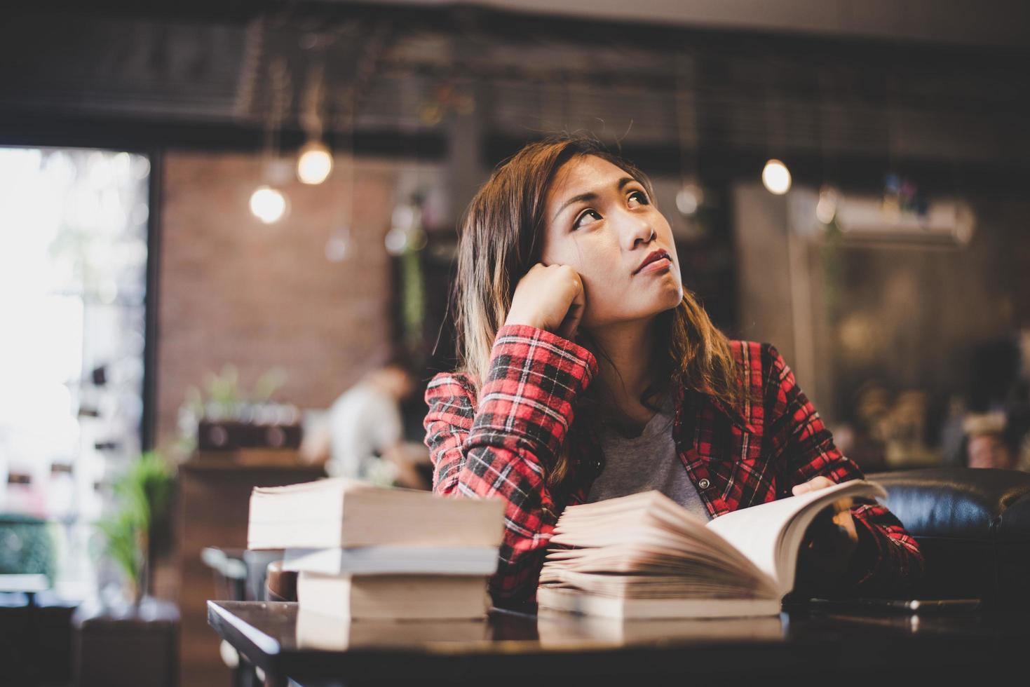 hipster kvinna tonåring sitter njuta av att läsa bok på café. foto
