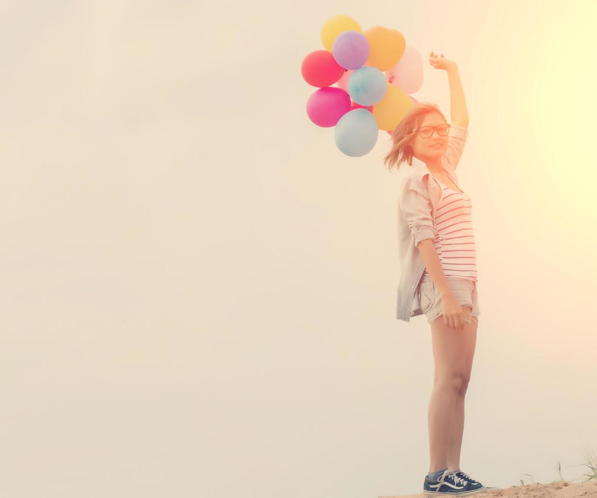 en vacker ung kvinna som håller ballonger på stranden foto