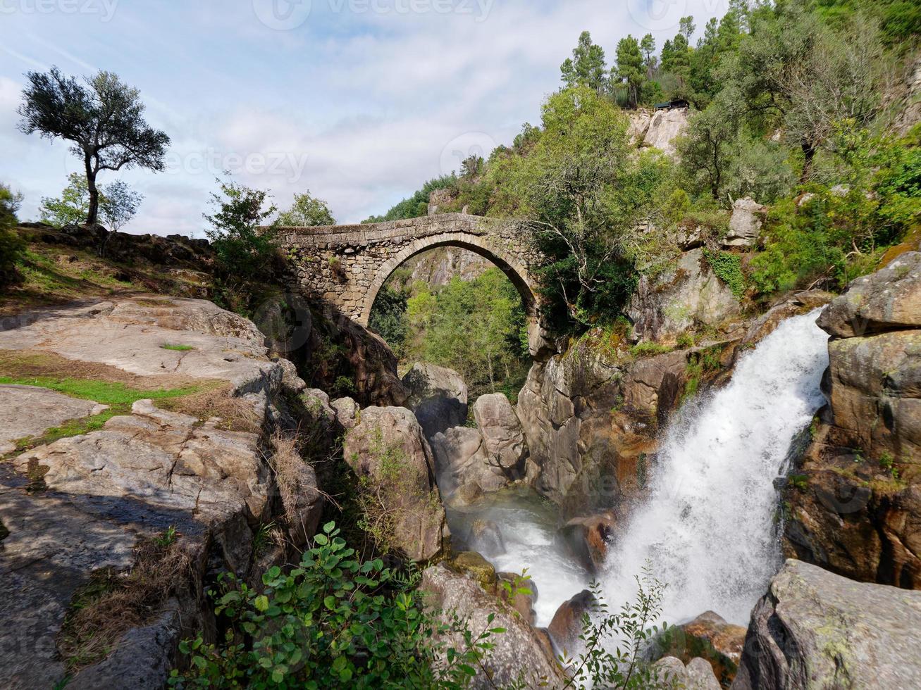 ponte da misarela eller bro av mizarela i montalegre, portugal med en stor vattenfall Nästa till den under en solig dag. lantlig resa och högtider i natur. foto