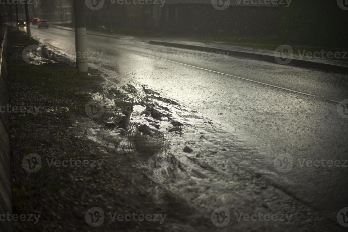 våt väg i regn. pöl på motorväg. smutsig vid vägkanten. foto