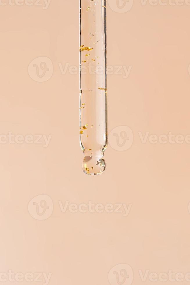närbild pipett med en hyaluronisk fuktgivande 24k guld serum på en beige bakgrund. skönhet hud vård begrepp skönhet och spa. foto