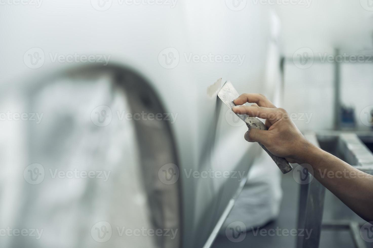 en skicklig målare detailing en professionell bil måla primer medan putsning en skinande vit bil, bil detaljering, bil tvätta och måla reparera. beskurna bild selektiv fokus foto