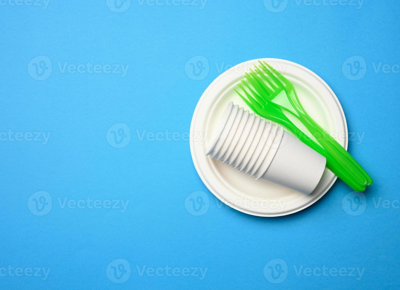 grön plast gafflar och tömma vit papper disponibel plattor på en blå bakgrund, foto