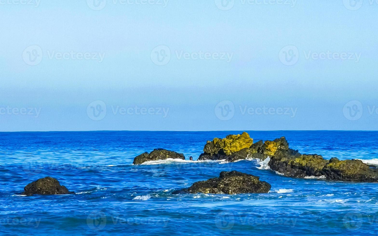 skön stenar klippor surfare vågor på strand puerto escondido Mexiko. foto