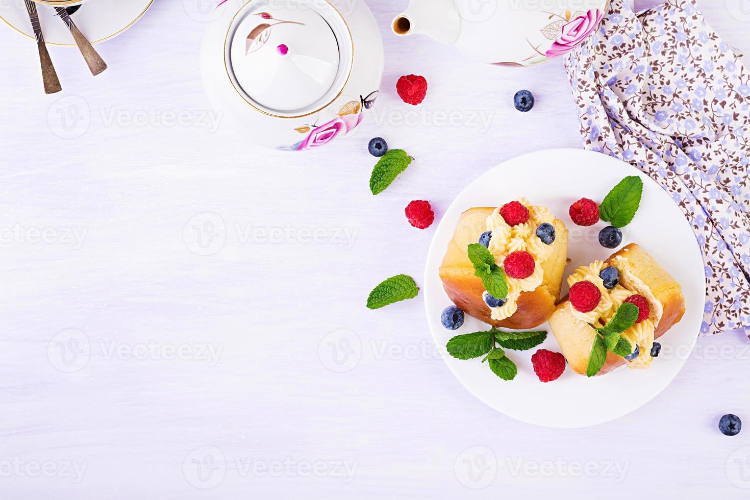 rom baba dekorerad med vispad grädde och färsk hallon, blåbär. savarin med rom, grädde och bär. italiensk kök. topp se foto