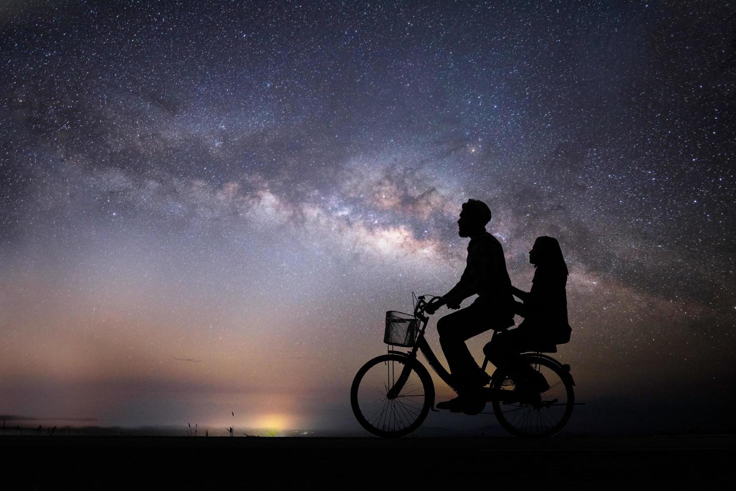 silhuett ungt par i kärlek njuta av god tid tillsammans under Vintergatan foto