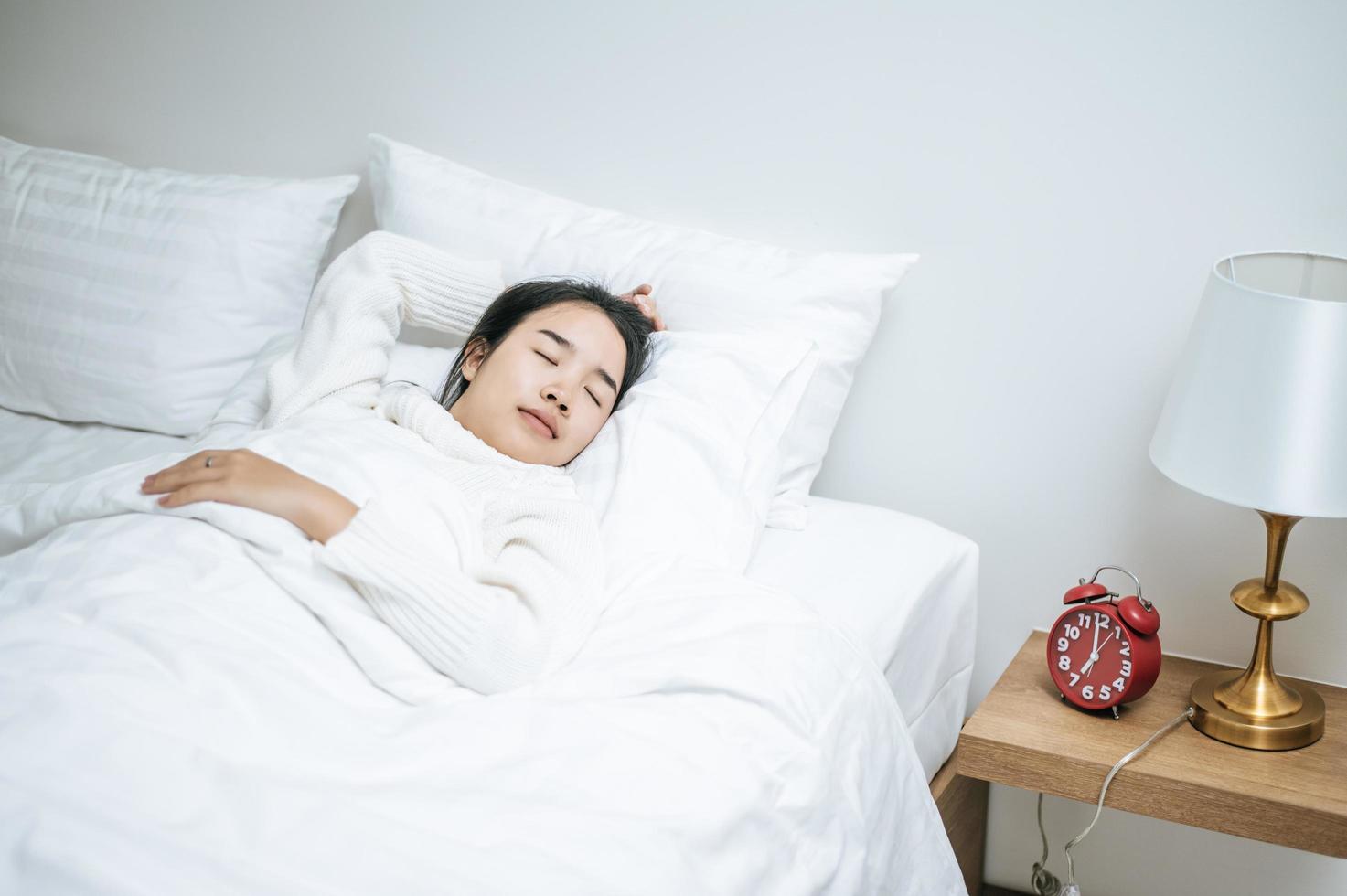 ung kvinna som bär vit skjorta som bara vaknar upp i sängen foto