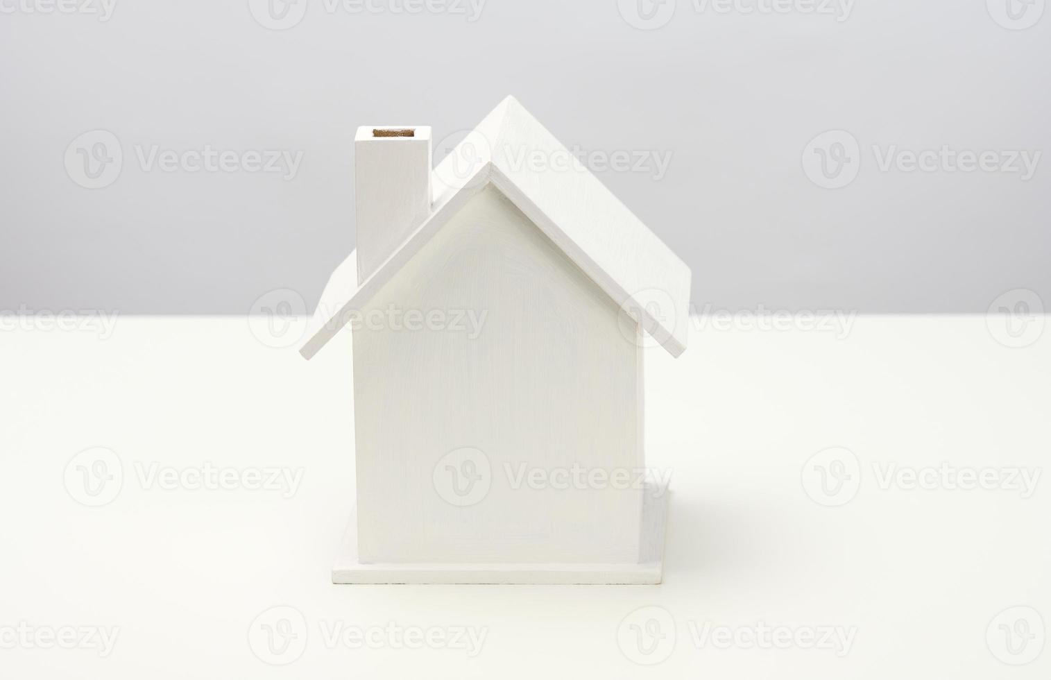 vit trä- hus på en grå bakgrund. verklig egendom uthyrning, inköp och försäljning begrepp. fastighetsmäklare tjänster, byggnad reparera och underhåll foto
