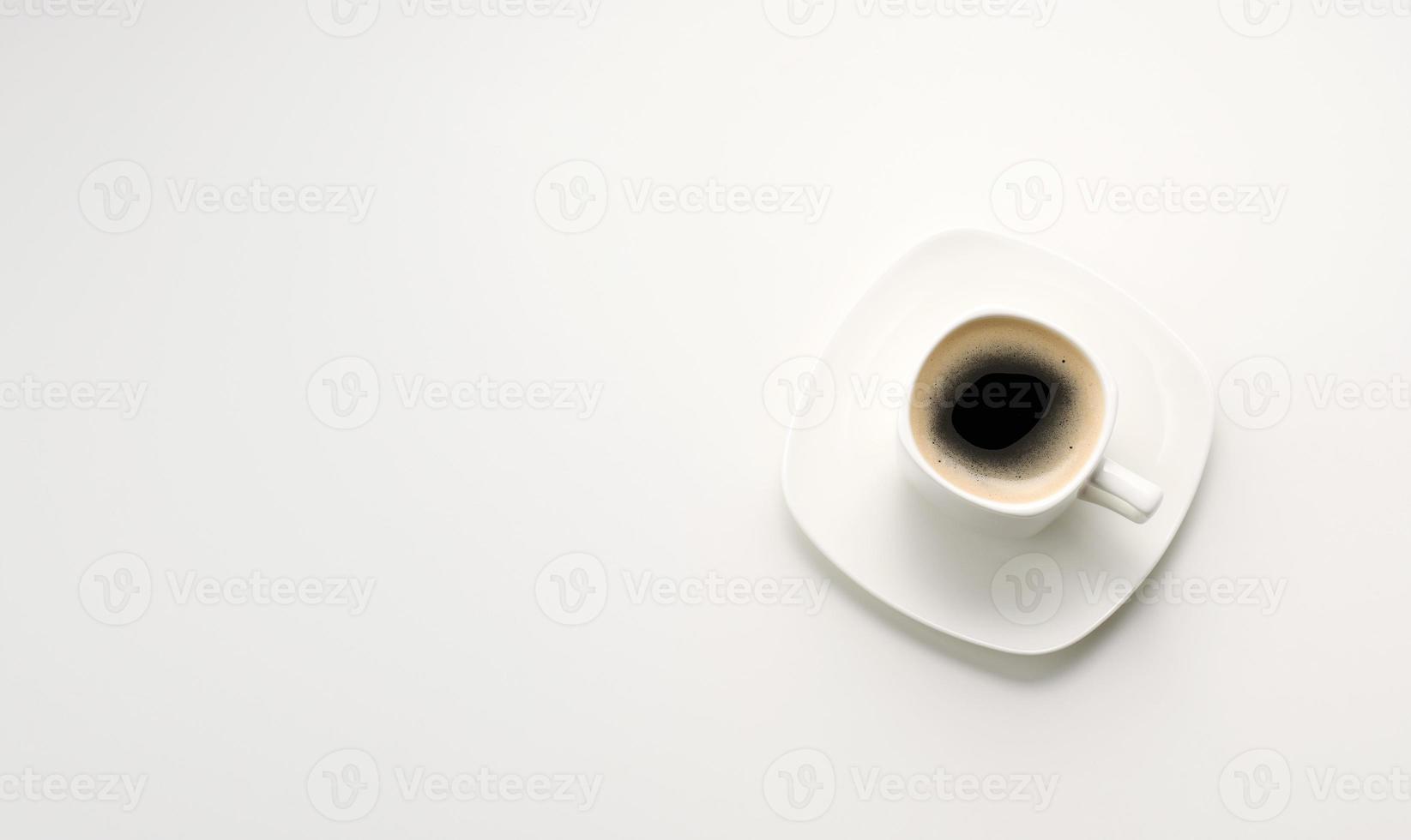 svart espresso kaffe i vit keramisk kopp med fat på vit tabell, topp se foto