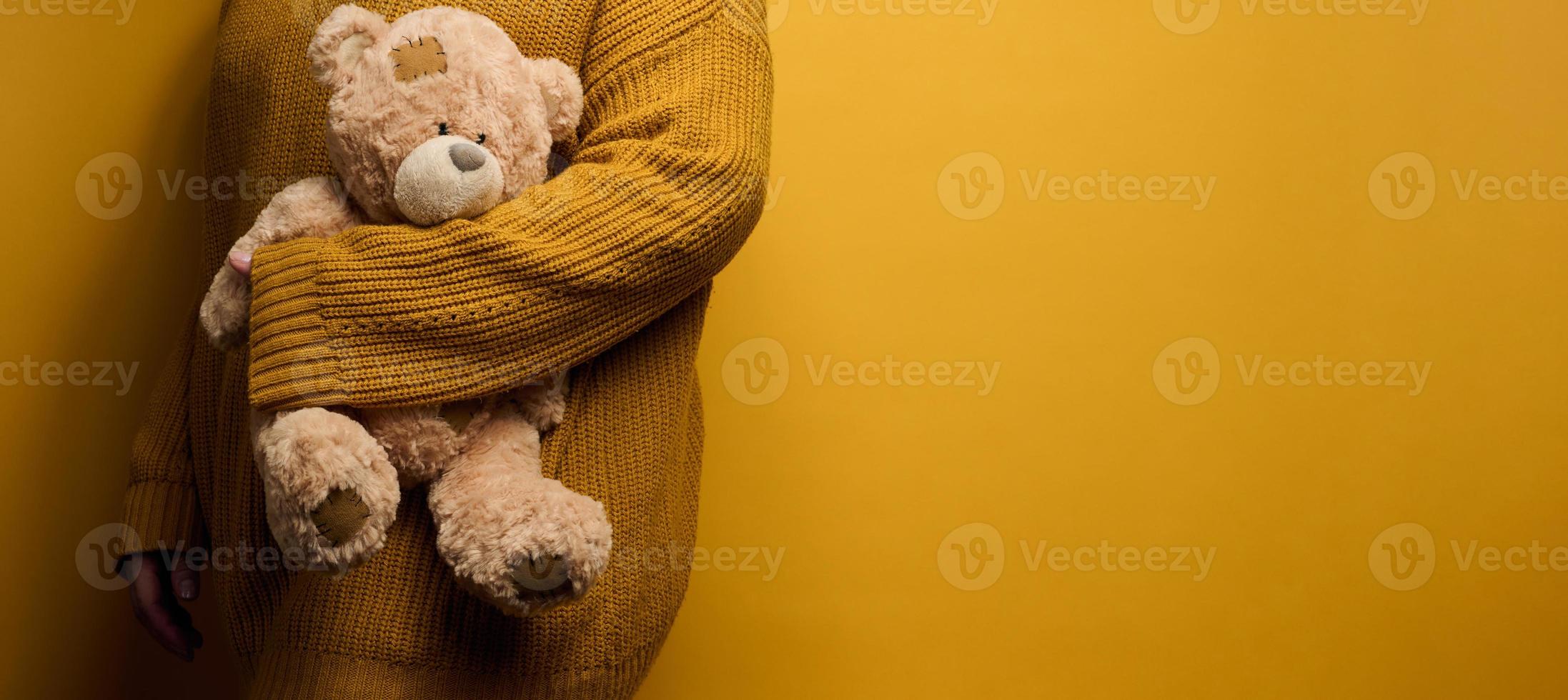 kvinna i orange stickat Tröja kramar söt brun teddy Björn. de begrepp av ensamhet och sorg, depression foto