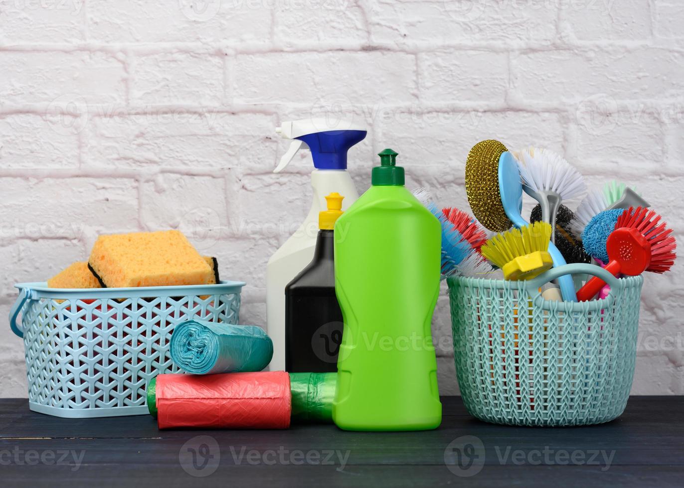 svampar, plast borstar och flaskor av tvättmedel på en blå trä- tabell. hushåll rengöring objekt foto