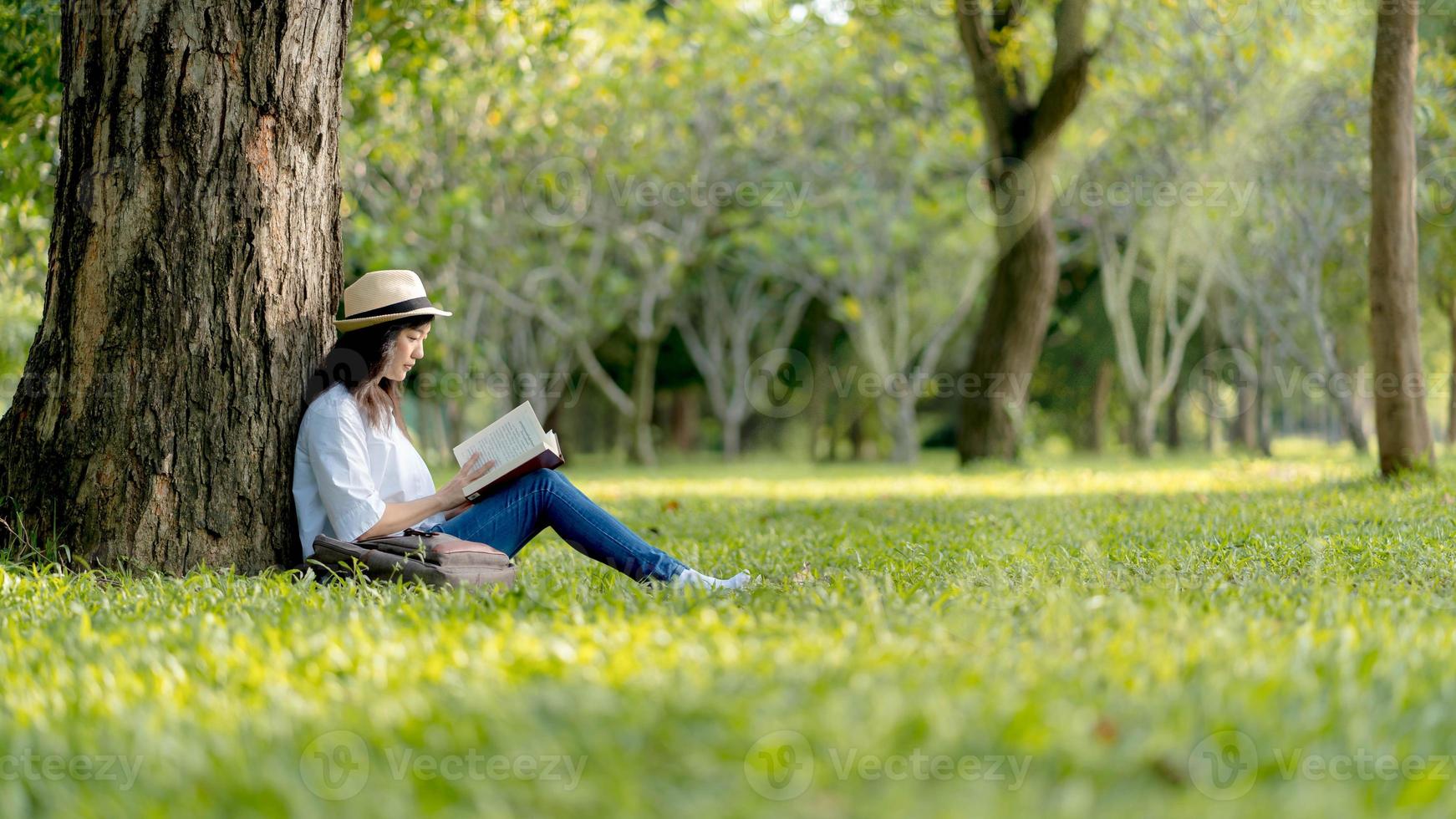 en skön asiatisk kvinna njuter och koppla av från läsning bok i de park.koncept av rekreation, utbildning och studie , nyfikenhet, fritid tid foto