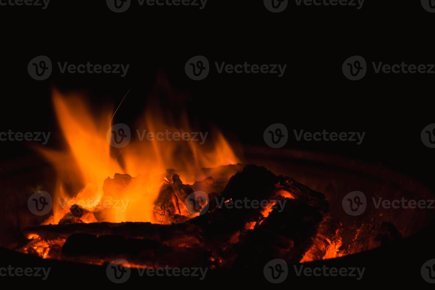 en flamma brinnande i en brasa i de mörk foto